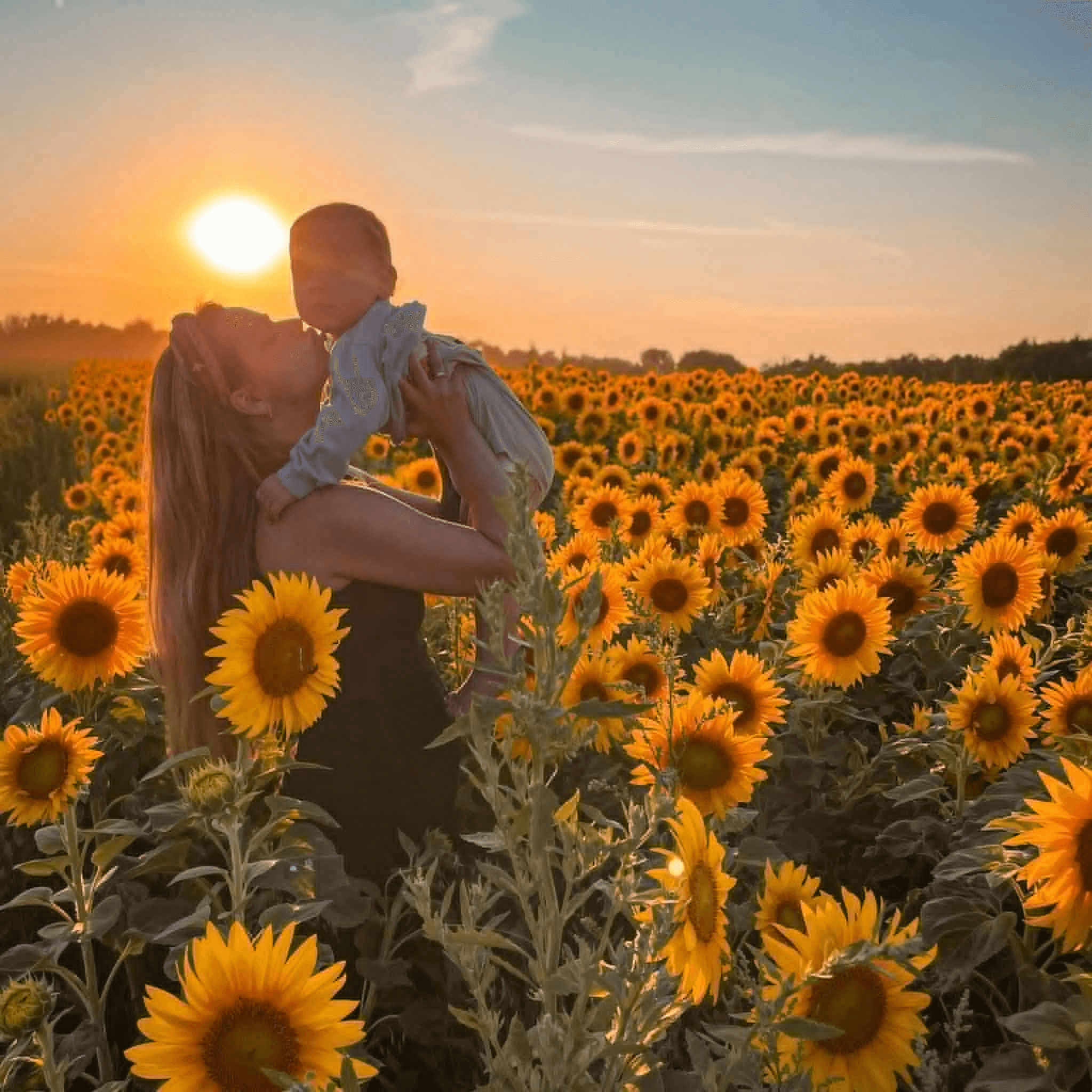 Mama trzymająca dziecko na rękach w polu słoneczników